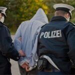 Mann mit Kapuze verhaftet von zwei Polizisten