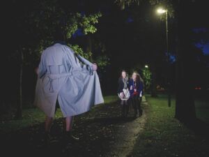 Nackter Mann öffnet den Mantel vor zwei Frauen