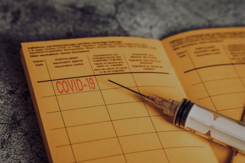 Gelber Impfpass mit COVID-19 Stempel und Spritze