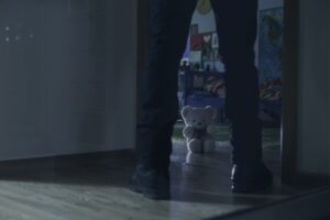 Mann schaut in Kinderzimmer mit Teddybär am Boden