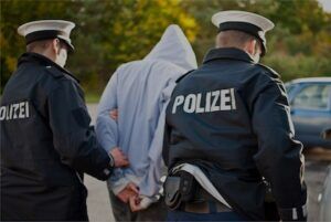 Mann mit Kapuze wird von zwei Polizisten verhaftet